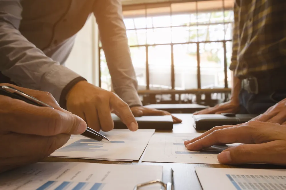 Equipe apontando dados em relatórios sobre a mesa