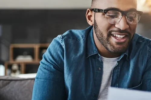 Homem de óculos e camisa jeans sorrindo durante uma conversa