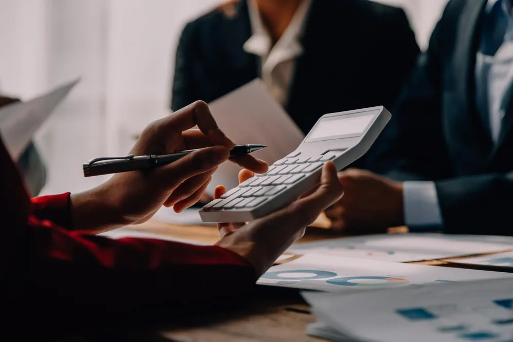 Mãos conferindo números em uma calculadora