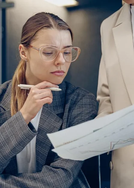 Mulher de óculos analisando um documento com uma caneta na mão