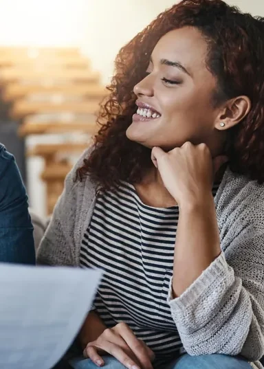 Mulher sorrindo, apoiada na mão, durante uma conversa